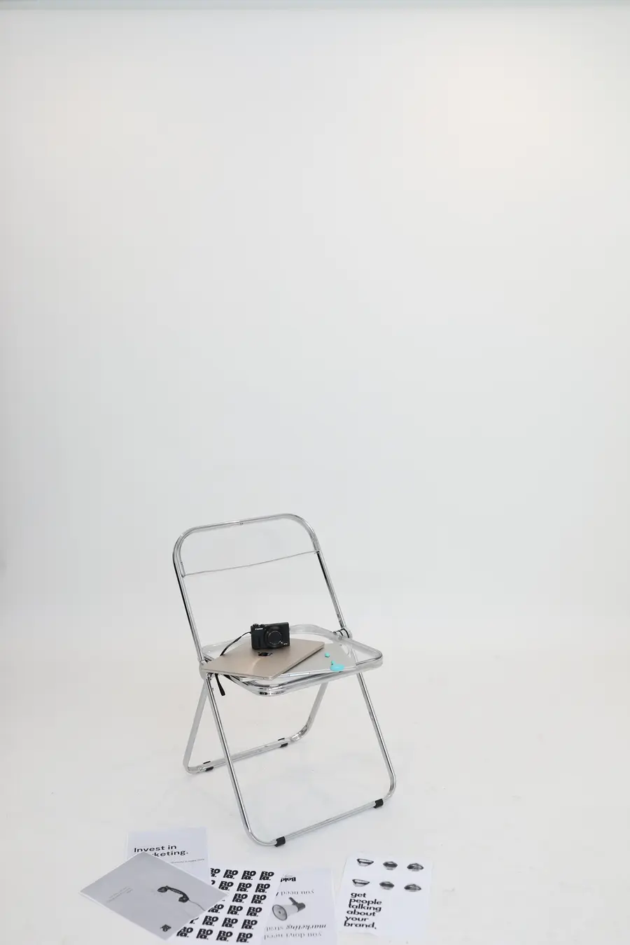 Bodegón de estudio con cámara, carteles y silla cromada
